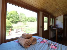 A bedroom with towels on the bed and a large window showing outdoor greenery at Celyn in Bontddu near Dolgellau
