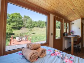 A bedroom with rolled towels on bed next to large window and a table with chairs at Celyn in Bontddu near Dolgellau