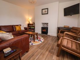 A living room with a sofa, armchairs, and a fireplace at Isfryn