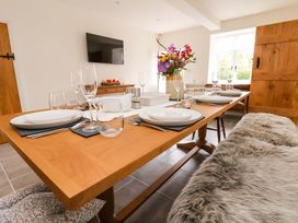 A dining room with a large table and flower arrangement at Isfryn in 