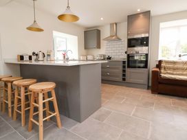 A kitchen with bar stools and appliances at Isfryn