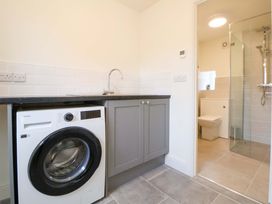 A laundry room with a washing machine and a shower at Isfryn
