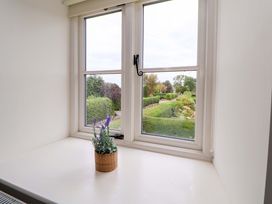 A windowsill with a plant and a view of the garden at Isfryn 