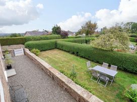 A garden with a table and chairs surrounded by hedges at Isfryn