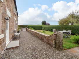 A garden with a stone wall and gravel path at Isfryn
