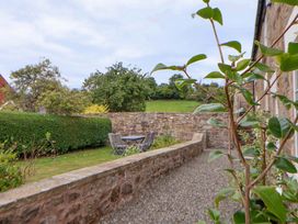 A garden with a stone wall and a table with chairs at Isfryn