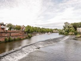 A river with a waterfall and boats along the bank at Isfryn Nercwys