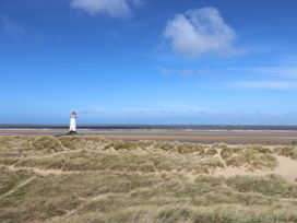 A lighthouse near the beach with sand dunes and ocean at Isfryn Nercwys