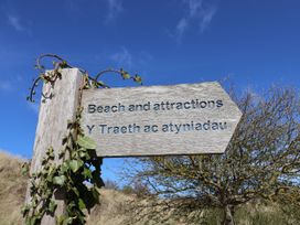 A wooden sign pointing to beach and attractions at Isfryn Nercwys
