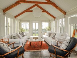A conservatory with a sofa and armchairs at Poldue House Watergate near Camelford
