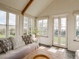 A conservatory with a sofa and coffee table at Poldue House near Camelford