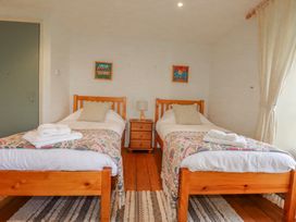 A bedroom with two beds and a bedside table at Poldue House Watergate near Camelford