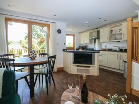 A kitchen with a dining area and windows at 2 Court Cottage in Dartmouth