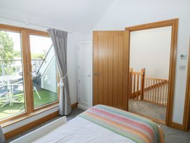 A bedroom with a bed and windows leading to a terrace at 2 Court Cottage Dartmouth