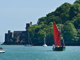 A sailboat on water near a castle with trees in the background at 2 Court Cottage, Hillfield Village Dartmouth