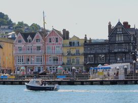 A waterfront view with buildings and a boat at 2 Court Cottage, Hillfield Village, Dartmouth