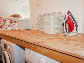 A laundry room with a washing machine and laundry supplies at Roughtor Barn Poldue near Camelford