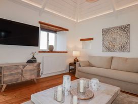 A living room with a television, sofa, and coffee table at Logan Barn near Poldue