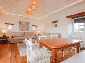 A living room with a sofa, table, and chairs at Logan Barn in Poldue near Camelford