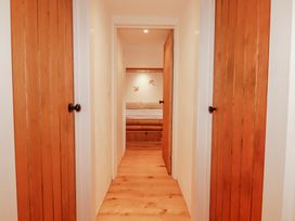 A hallway with wooden doors and a bed visible at Logan Barn in Poldue near Camelford