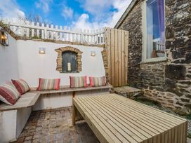 An outdoor seating area with cushions and a wooden table at Logan Barn in Poldue near Camelford