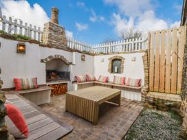 An outdoor seating area with a fireplace and coffee table at Logan Barn Poldue near Camelford