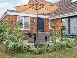 An outdoor seating area with a table and chairs under an umbrella at The West Wing in Potterne