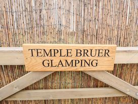 A wooden sign saying Temple Bruer Glamping on a wooden fence with bamboo backdrop at Shepherds Hut - Oak in Temple Bruer near Lincoln