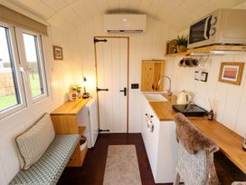 A compact kitchen and seating area with a bench and a chair in Shepherds Hut - Oak Temple Bruer near Lincoln