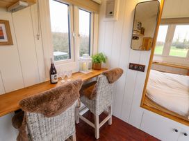 A small seating area with two chairs and a wooden counter by windows next to a bedroom at Shepherds Hut - Oak in Temple Bruer near Lincoln