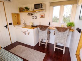 A small kitchen with a sink countertop microwave and two chairs by a window at Shepherds Hut - Oak in Temple Bruer near Lincoln