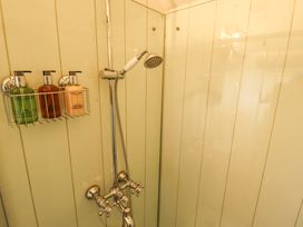 A shower area with a handheld showerhead and three dispensing bottles mounted on the wall at Shepherds Hut - Oak in Temple Bruer near Lincoln