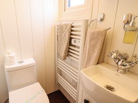 A small bathroom with a toilet a towel radiator with two towels and a sink with a soap dispenser at Shepherds Hut - Oak Temple Bruer near Lincoln