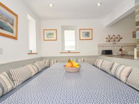 A kitchen with a table and cushions at Seaworthy in Daymer Bay