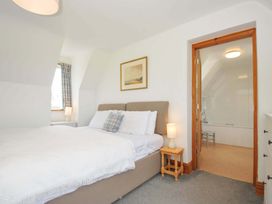 A bedroom with a bed and an adjoining bathroom at Seaworthy in Daymer Bay