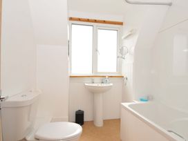 A bathroom with toilet, sink, mirror and bathtub at Seaworthy in Daymer Bay