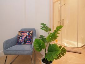 A chair with a cushion next to a shower in a bathroom at 2 The Old School House