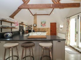 A kitchen with a central island and bar stools at Cottage - 1 bedroom Broadway