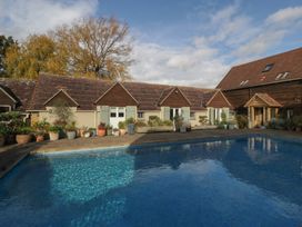 A swimming pool next to buildings with potted plants at Cottage - 1 bedroom in Broadway