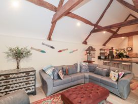 A living room with a sofa and a kitchen area at Garden Cottage in Saintbury near Broadway