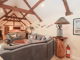 A living room with a sofa and lamp at Garden Cottage in Saintbury near Broadway