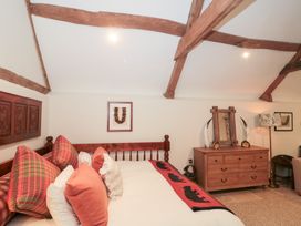 A bedroom with a wooden bed and chest of drawers at Garden Cottage in Saintbury near Broadway