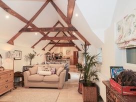 A living room with a sofa and kitchen area at Garden Cottage in Saintbury near Broadway