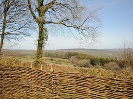 A woven wooden fence with trees and rolling hills in the background at Rose Cottage in Callington