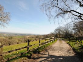 A dirt road next to a wooden fence with fields and trees around Rose Cottage in Callington