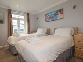A bedroom with two single beds and a window at Satinwood in White Cross near Newquay