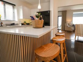 A kitchen with wooden stools at a breakfast bar and a basket on the counter at Buzzards View in Dyserth