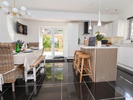 A kitchen with a dining table set with dishes and chairs next to a kitchen island with stools and pendant lights at Buzzards View in Dyserth