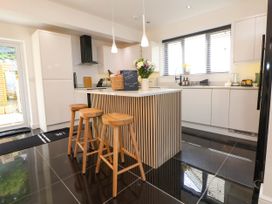 A kitchen with three wooden stools at an island under pendant lights at Buzzards View in Dyserth