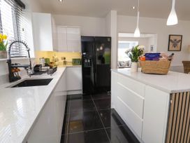 A kitchen with white cabinets black refrigerator and a countertop with a basket of groceries and flowers at Buzzards View in Dyserth